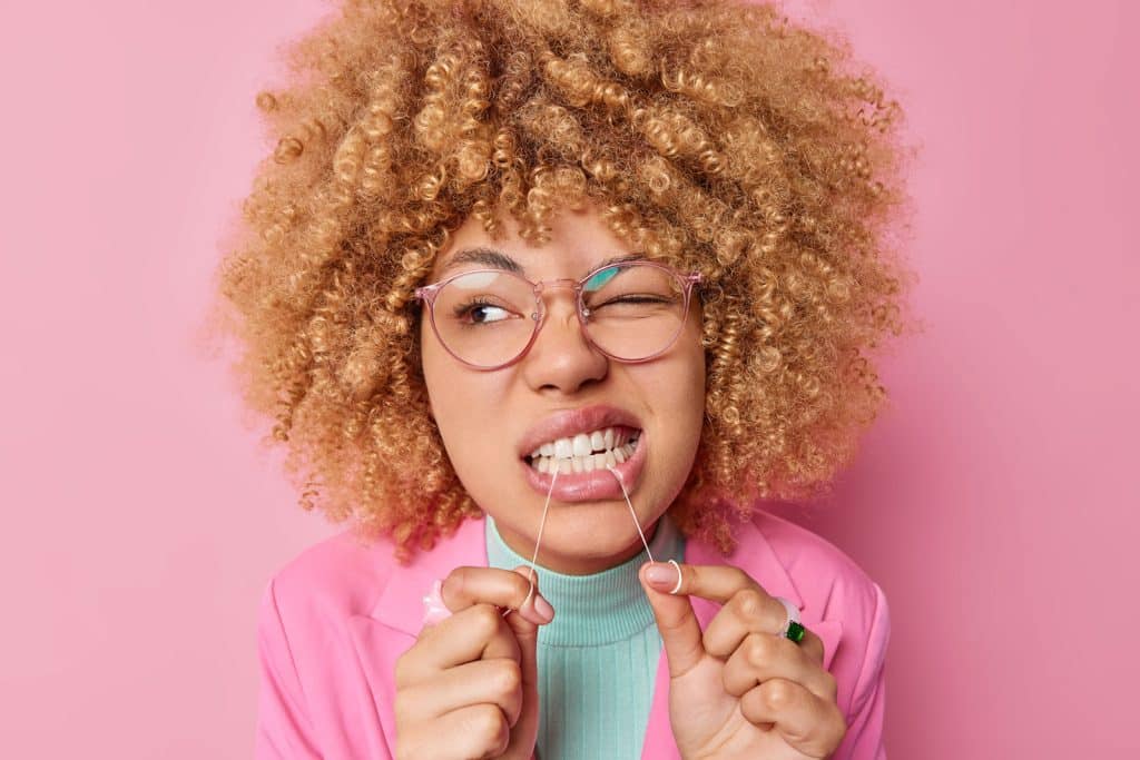 Woman flossing teeth wearing pink