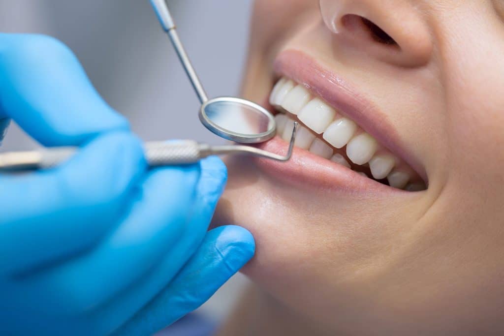 female with straight white teeth getting dental checkup