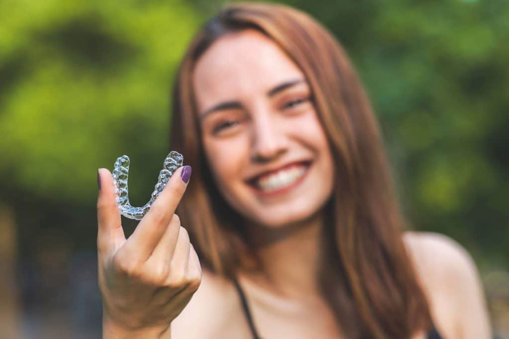 women smiling holding clear mouthguard